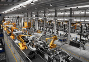 High angle view of cars on production line in factory. Many robottic arms doing welding on car metal body in manufacturing plant. Image in 3D render.